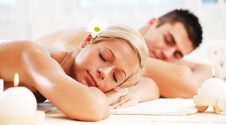 Un homme et une femme alongée sur le ventre, les yeux fermer pour un massage